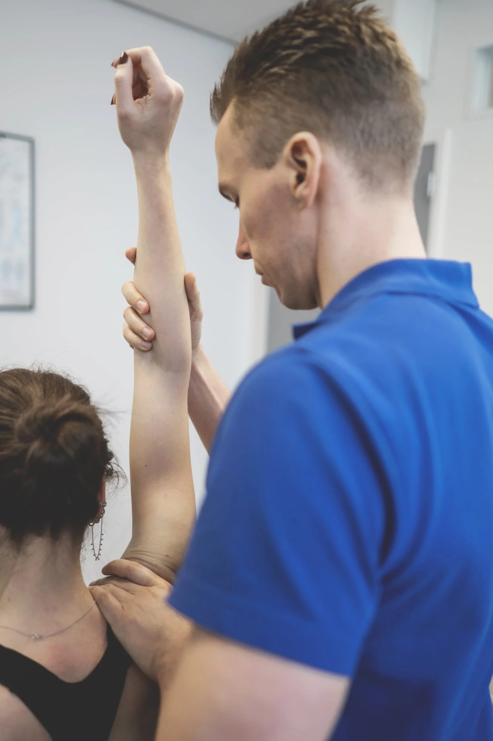Fysiotherapeut van Fysiotherapie Bunde onderzoekt de schouder van een patiënte