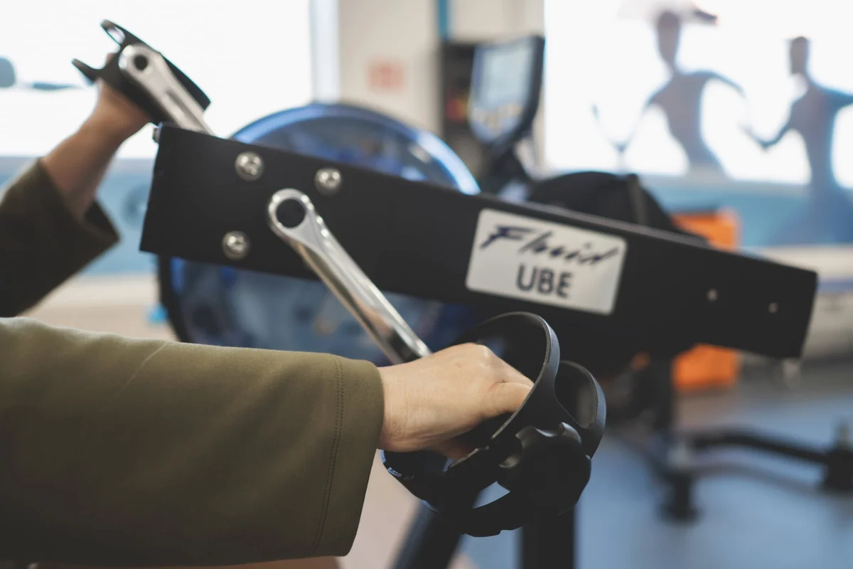 Oudere patiënt traint op een armfiets in de oefenzaal