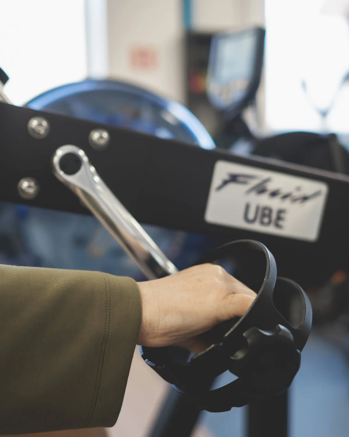 Oudere patiënt traint op een armfiets in de oefenzaal