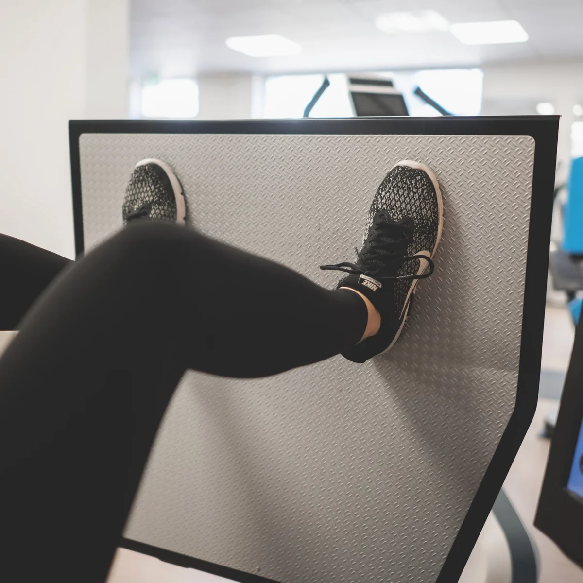 Patiënt traint op een beenpers met een digitaal trainingsscherm