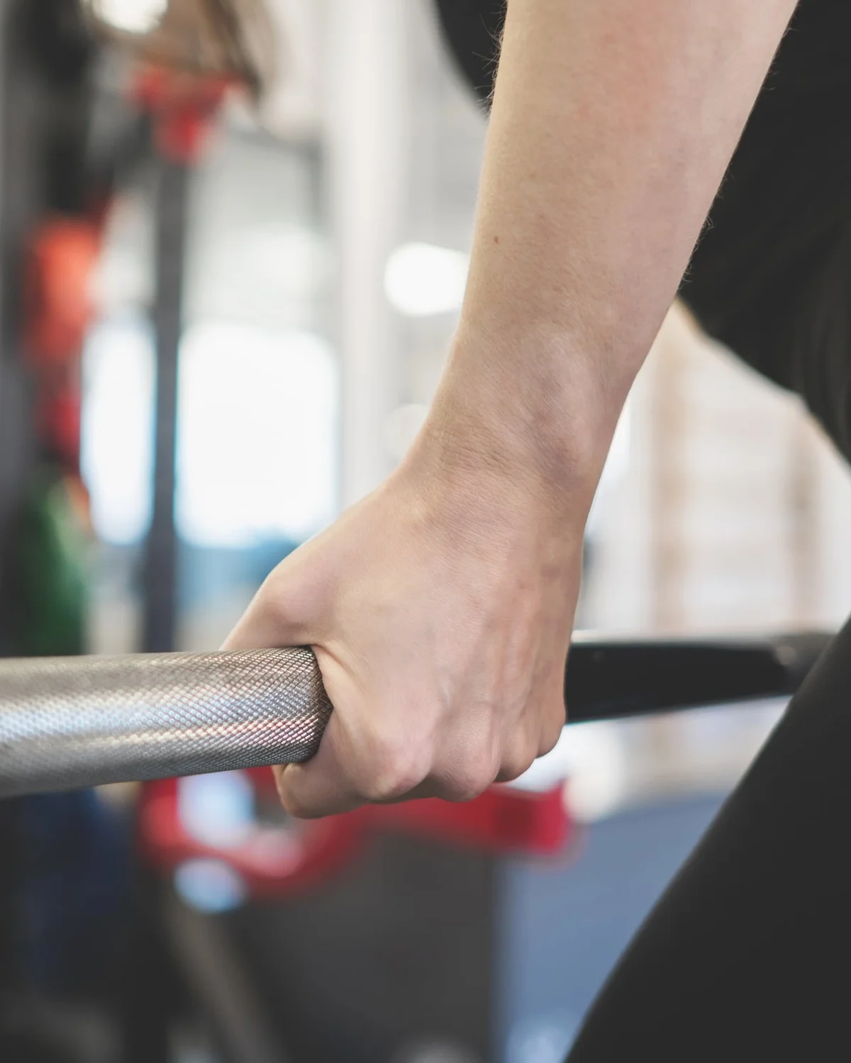 Hand aan een halterstang in de trainingsruimte